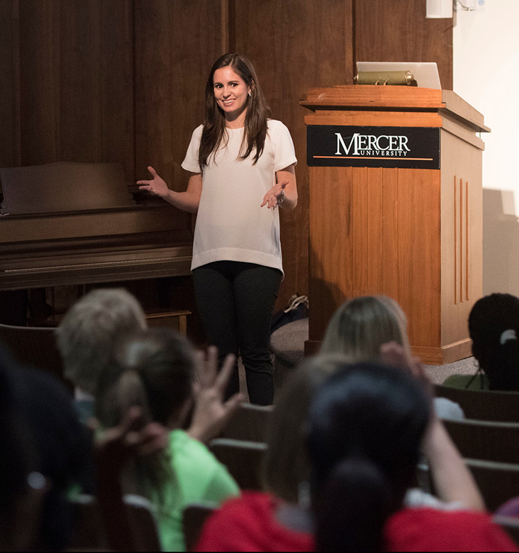 Person standing in front of lectern with the Mercer University wordmark speaking to an audience