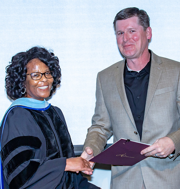 Dr. Gail Johnson shaking the hand of a person holding a folder