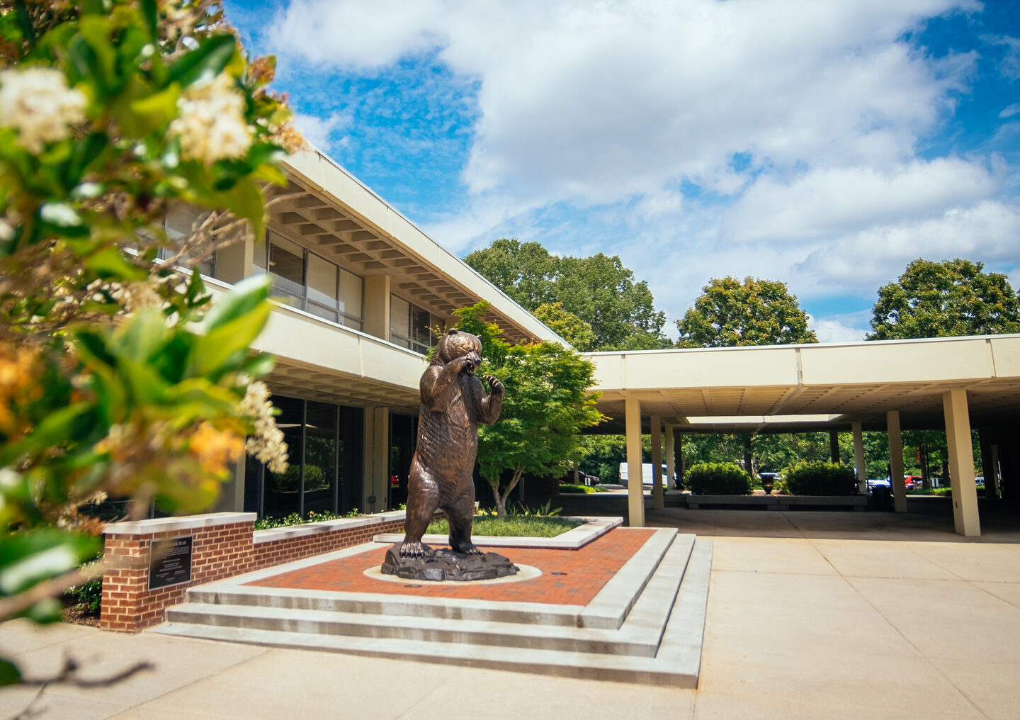 Bear statue on Mercer's Atlanta campus. Blue sky, flowers in bloom.
