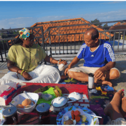 a female counseling student sits with a male on a picnic blanket outdoors