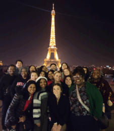 group of counseling students smiling in front of the Eiffel tower at night