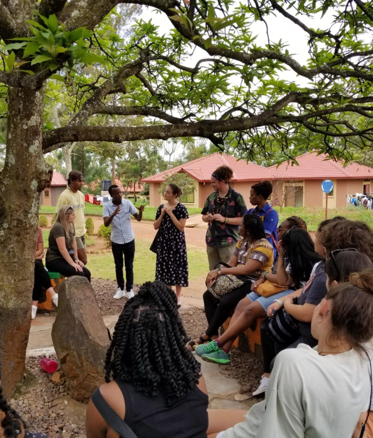 Counseling students standing in a circle outdoors by a tree