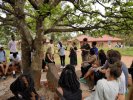 group of people standing outside around a tree