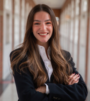 Dr. Bullard posing with arms crossed, wearing a navy blue jacket in a hallway