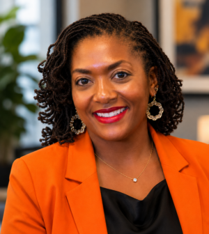 dr. nadia barnett posing for a headshot while wearing an orange blazer and smiling